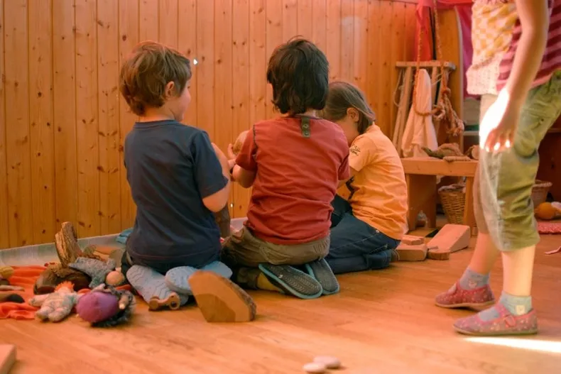 Niños compartiendo un juego en una sala de materiales nobles